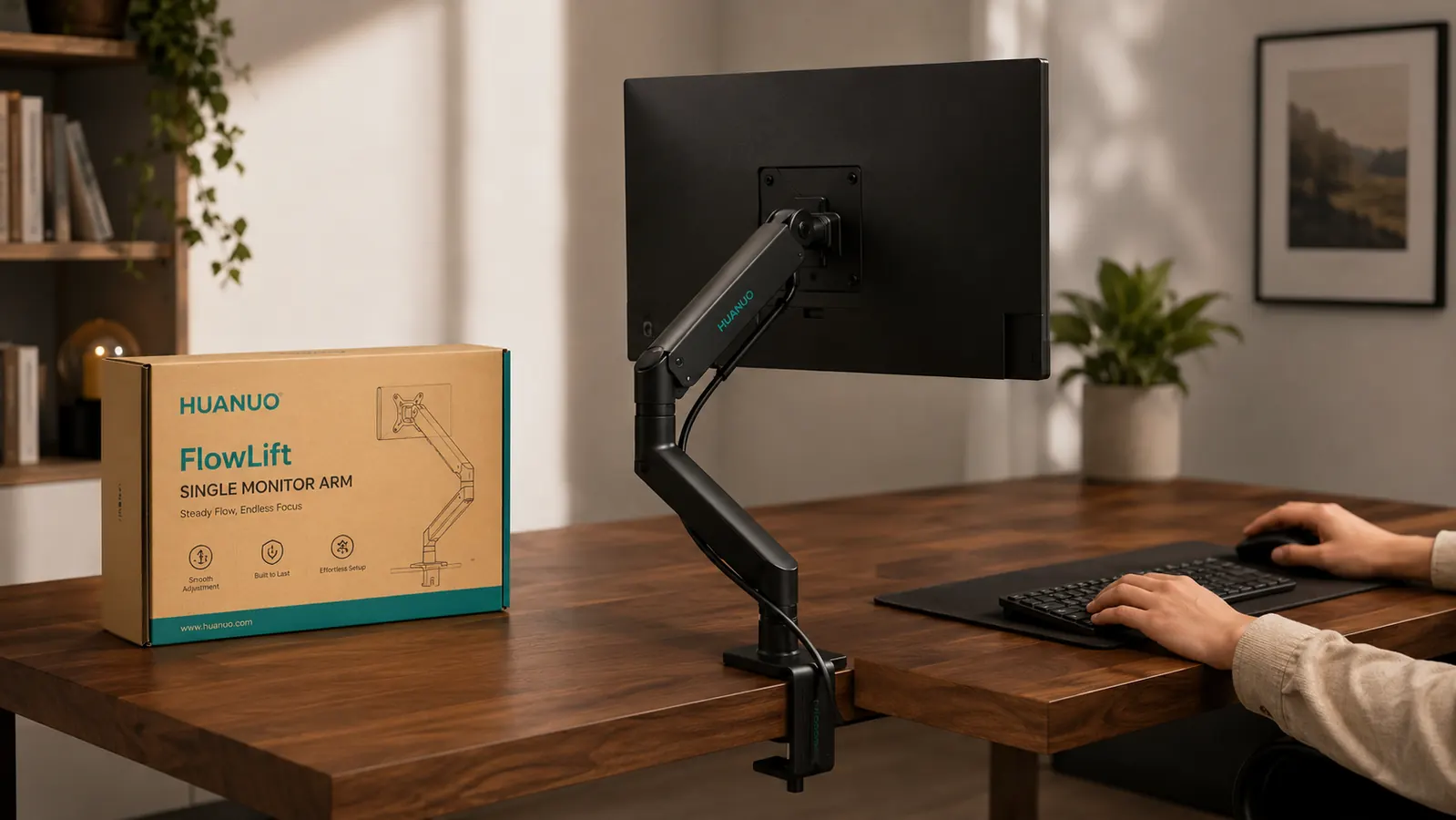 Monitor arm clamped to the back edge of a wooden desk, monitor raised to eye level, cable routed along the arm