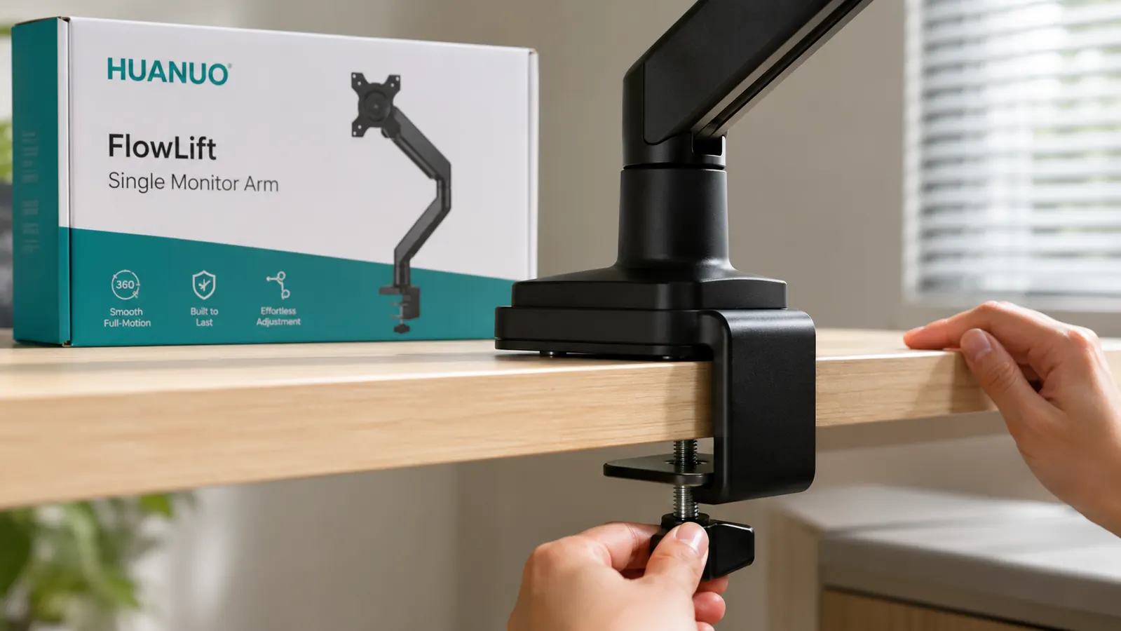 Monitor arm clamp base attached to a wooden desk edge, rubber pad visible, showing the clamping hardware from the side