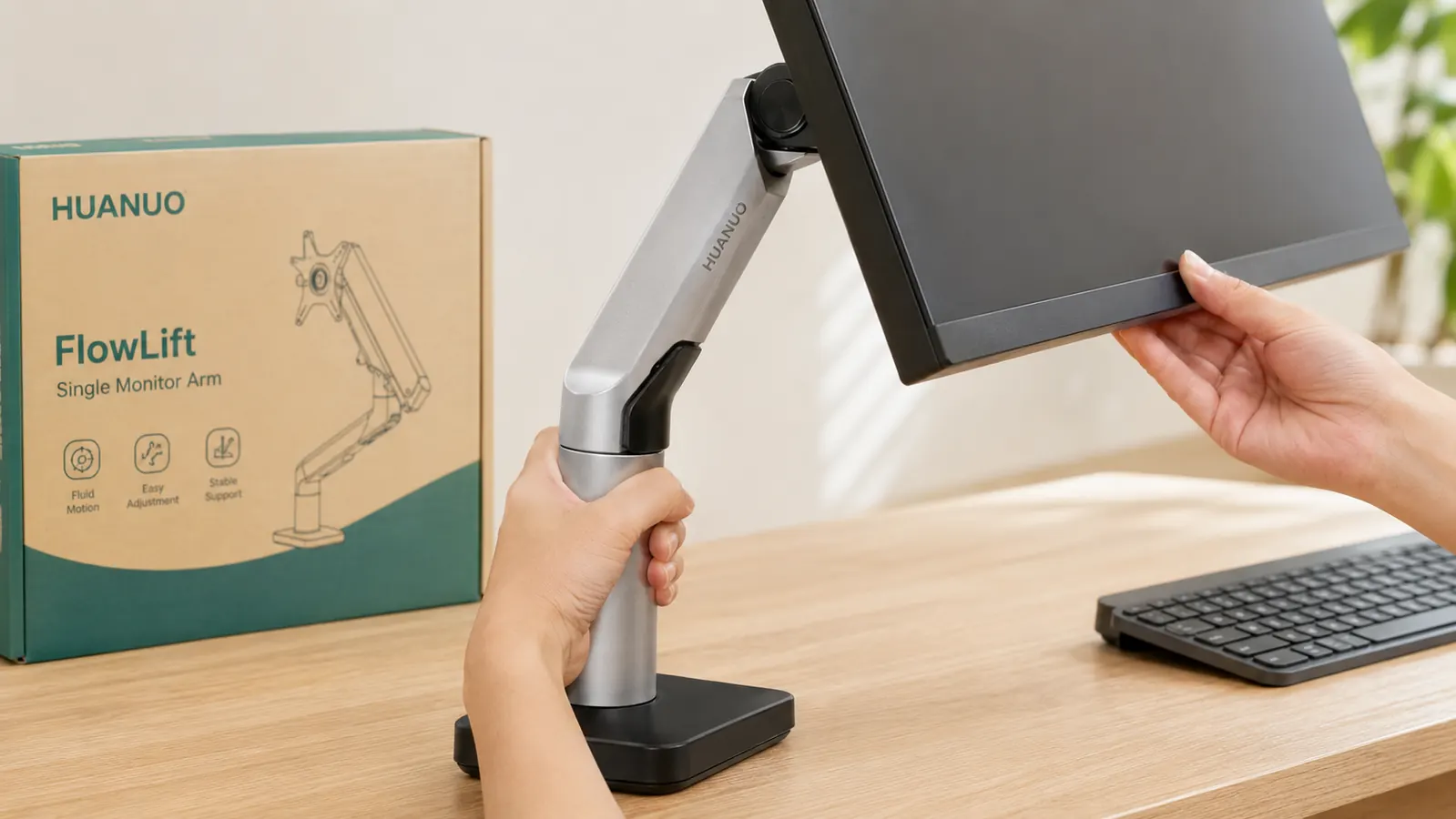 Hand adjusting the height of a monitor arm, monitor tilted slightly downward, desk surface visible below